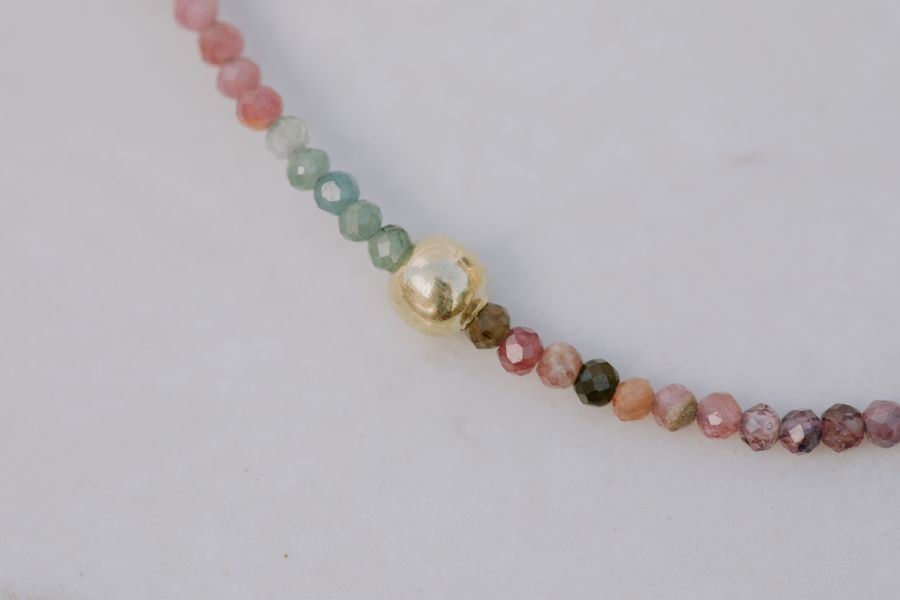 Primer plano una pulsera con cuentas facetadas de piedra semipreciosa en Turmalina Multicolor y bañadas en Oro de 18 quilates con cierre de gancho bañado en oro de 18 quilates