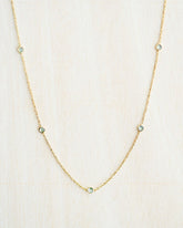 Collar bañado en oro de 18k con piedras de Aqua Calcedonia sobre fondo claro de Isla Vurma 