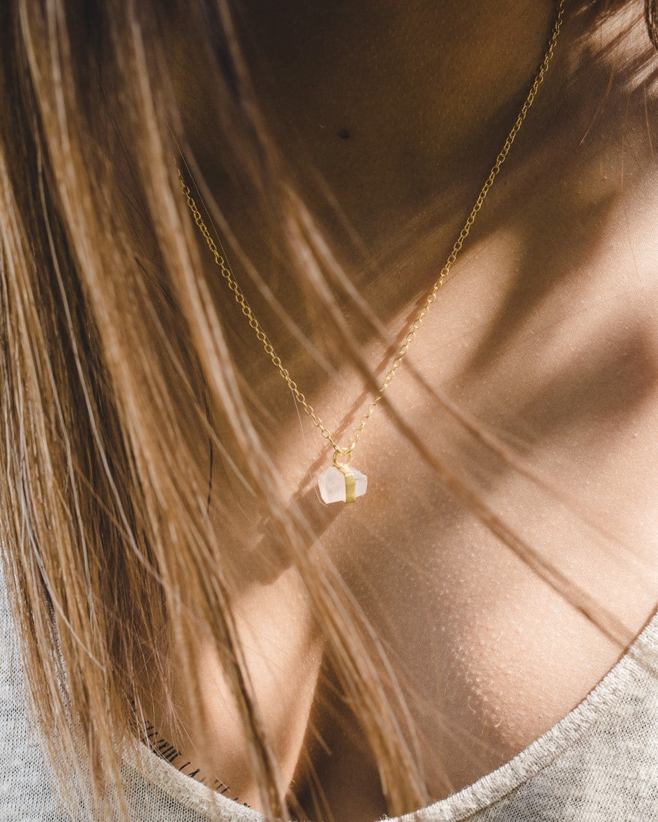 Primer plano del cuello de la modelo con el collar bañado en oro de 18 quilates con piedra semipreciosa de Cuarzo Rosa sujeta por una pequeña pieza dorada de Isla Vurma
