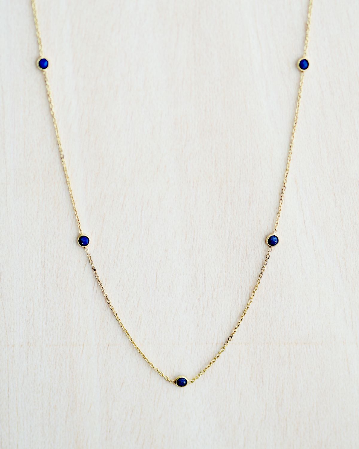 Collar bañado en oro de 18k con piedras de Lapislázuli sobre fondo claro de Isla Vurma 