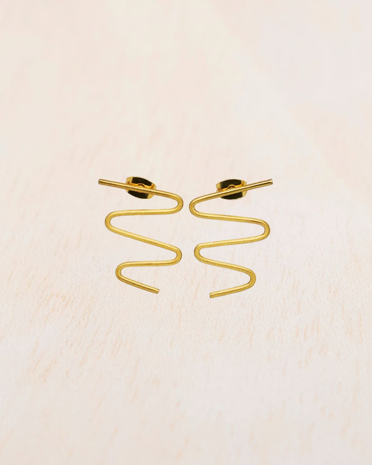 Primer plano de los pendientes dorados con forma ondulada